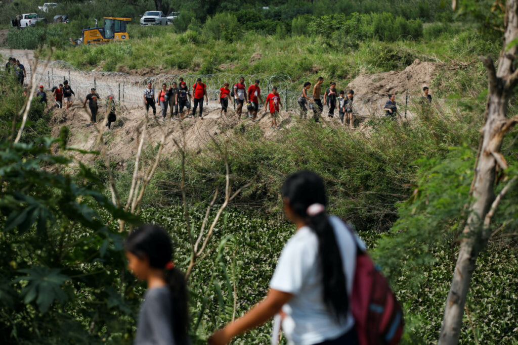 Migrants walk along the banks of the Rio Bravo river after crossing the border to turn themselves in to US Border Patrol agents before the lifting of Title 42, as seen from Matamoros, Mexico, on 11th May, 2023.