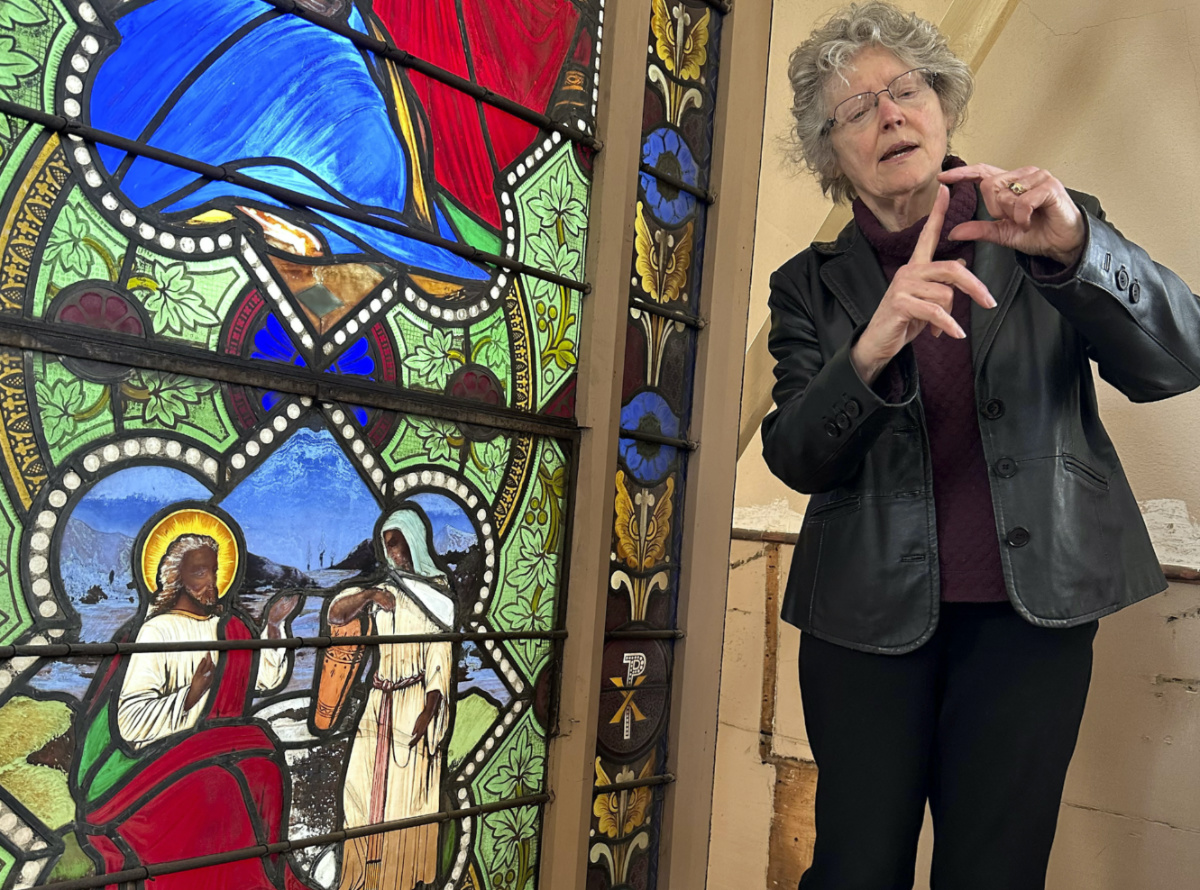 Holy Cross professor and stained-glass expert Virginia Raguin speaks to a group of middle school students, on Monday, 1st May, 2023, while standing near a nearly 150-year-old stained-glass window that depicts Christ speaking to a Samaritan woman, in the now-closed St Mark's Episcopal church, in Warren, Rhode Island.