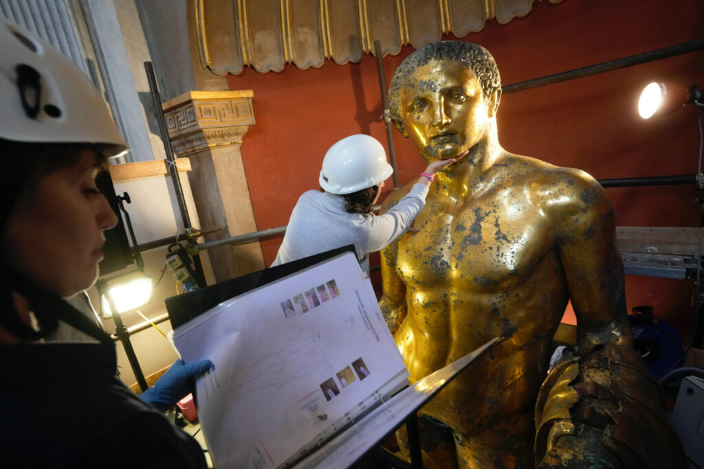 Vatican Museum restorers Chiara Omodei Zorini, left, and Alice Baltera work on the bronze Hercules statue, in the Round Hall of the Vatican Museums, on Thursday, 11th May, 2023.