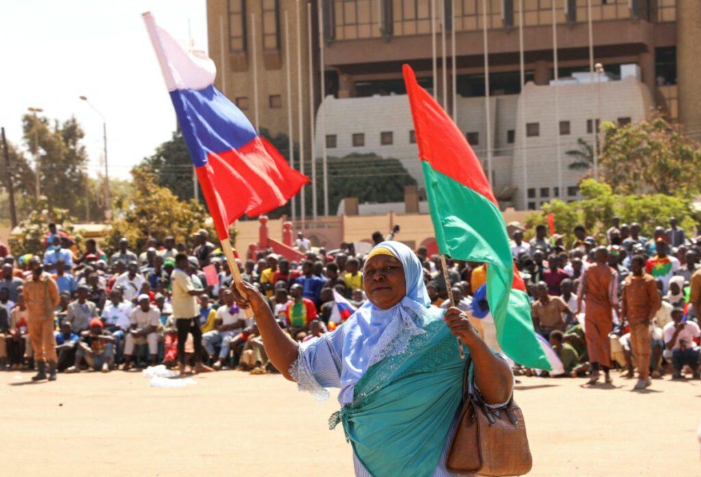 A woman holds her national flag and the Russian flag as people gather to show their support they gather to show their support to Burkina Faso's new military leader Ibrahim Traore and demand the departure of the French ambassador at the Place de la Nation in Ouagadougou, Burkina Faso, on 20th January, 2023.