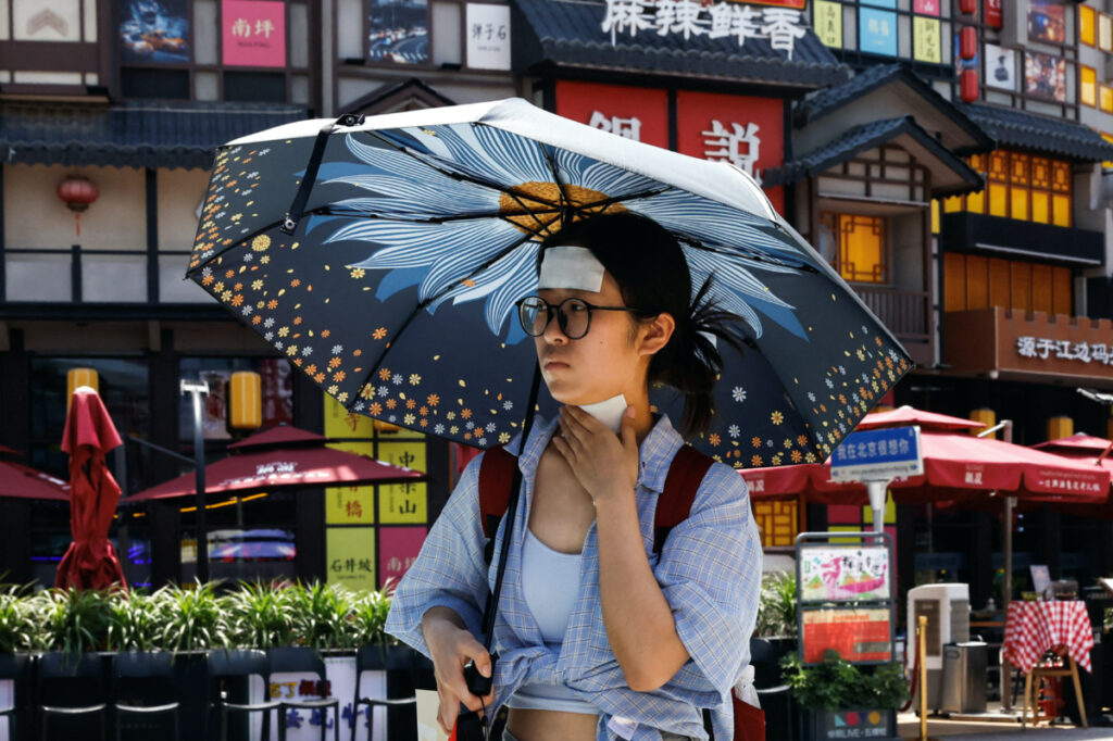 A woman walks with cold patches on her forehead and neck amid a red alert for heatwave in Beijing, China, on 23rd June, 2023