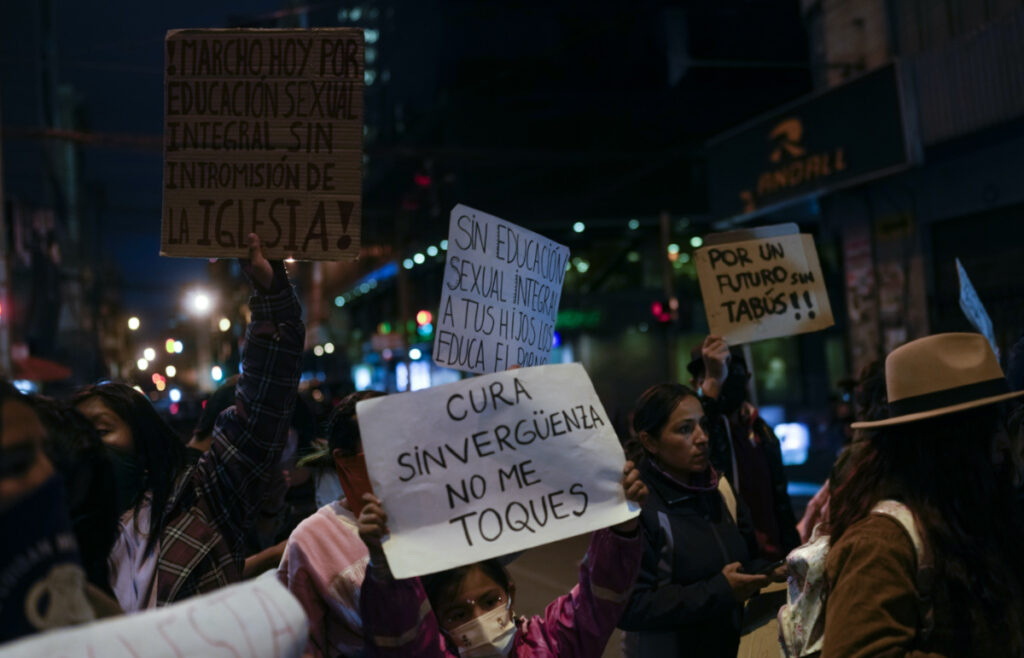 People protest with signs that read in Spanish "Shameless priest do not touch me" and "I march for sexual education without church interference," outside the offices of the Bolivian Episcopal Conference in La Paz, Bolivia, on Monday, 15th May, 2023.