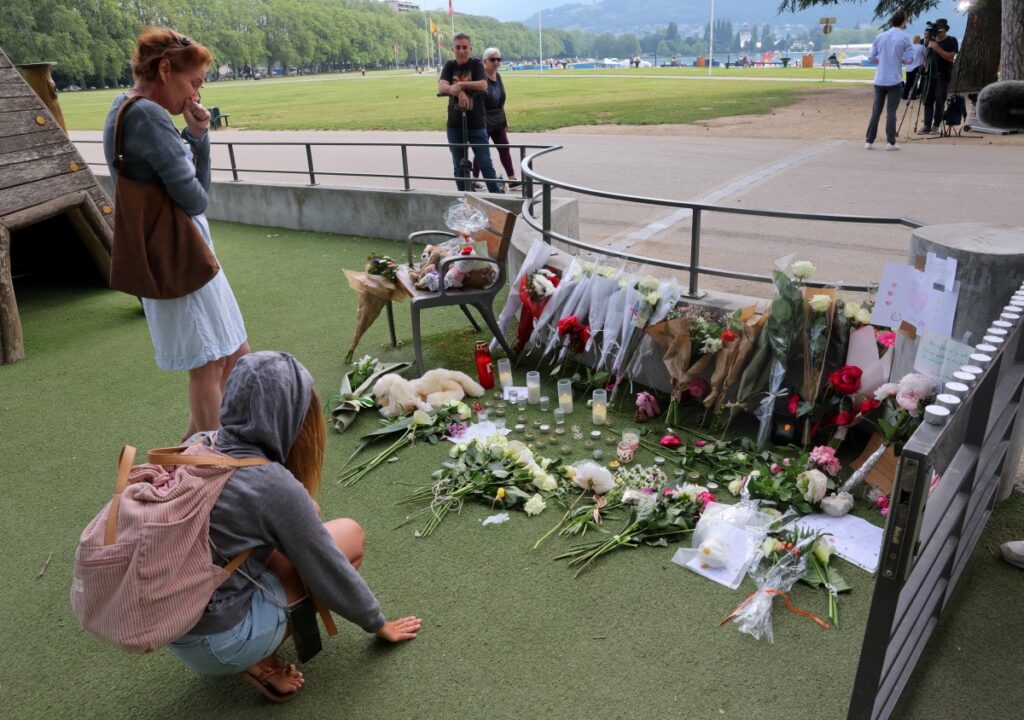 People pay respect in front of messages and floral tributes at the children's playground the day after several children and adults were injured in a knife attack at the Le Paquier park near the lake in Annecy, in the French Alps, France, on 9th June, 2023.