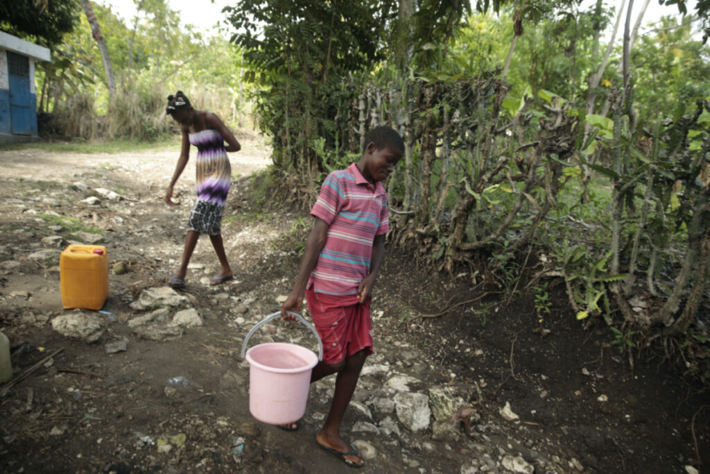 Siblings Mylouise Veillard, left, and Myson walk home with water they collected from a well, for cooking, cleaning and drinking, in a rural area of Saint-Louis-du-Sud, Haiti, on Thursday, 25th May, 2023.