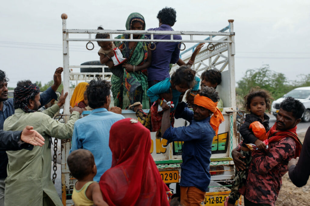 A man carries a child from a truck during an evacuation before the arrival of cyclone Biparjoy in Jakhau in the western state of Gujarat, India, on 14th June, 2023.