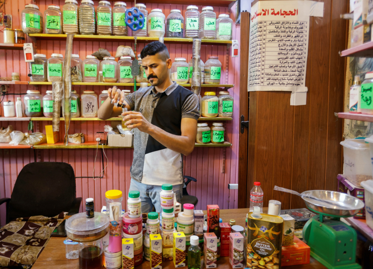 Hassan Abed Ali mixes different liquids meant for treatments, at his shop in Baghdad, Iraq, on 11th June, 2023.