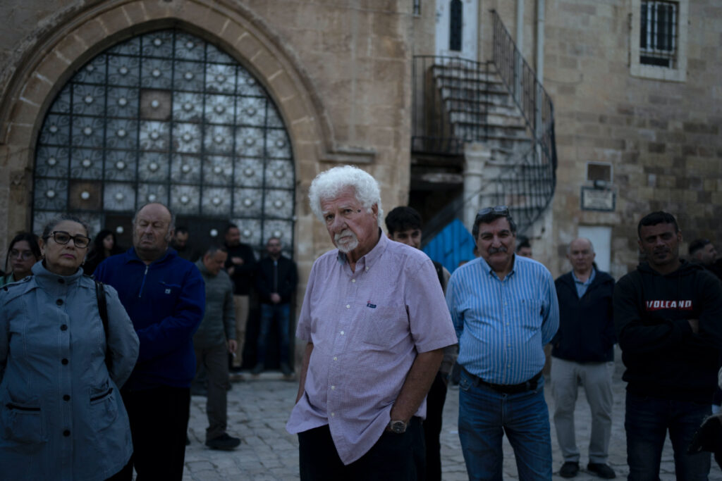 Garo Nalbandian, an 80-year-old photojournalist, centre, listens to a speaker during an Armenian community protest of a contentious deal that stands to displace him and other residents and cede some 25 per cent of the Armenian Quarter in the Old City of Jerusalem, on Friday, 19th May 2023.