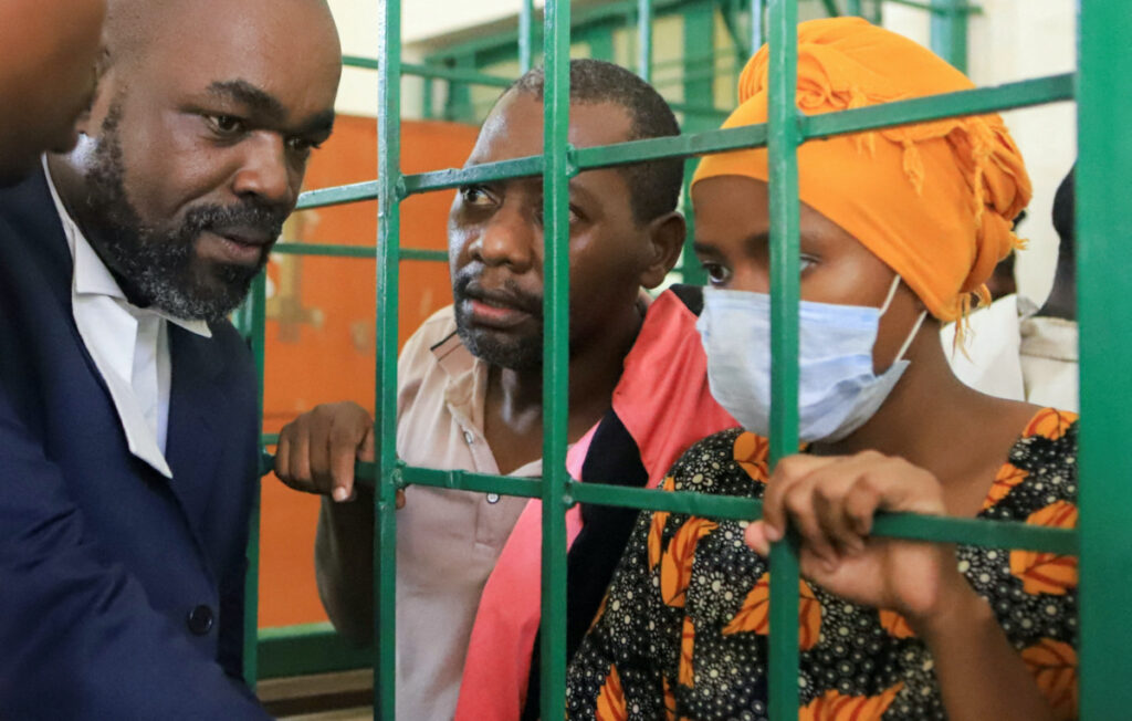 Paul Mackenzie, 50, a Kenyan cult leader accused of ordering his followers, who were members of the Good News International Church, to starve themselves to death in Shakahola forest, and his wife Rhoda Mumbua Maweu, speak to their lawyer George Kariuki from a steel-grilled dock at the Shanzu Law Courts, in Mombasa, Kenya, on 10th May, 2023.