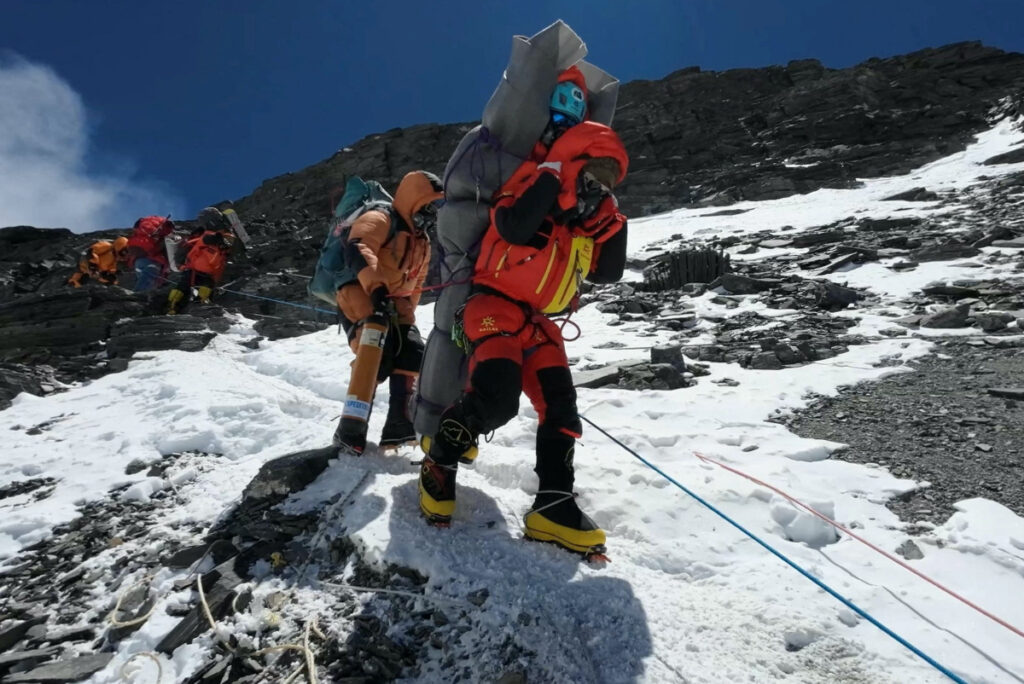 Ngima Tashi Sherpa walks as he carries a Malaysian climber while rescuing him from the death zone above camp four at Everest, Nepal, on 18th May, 2023