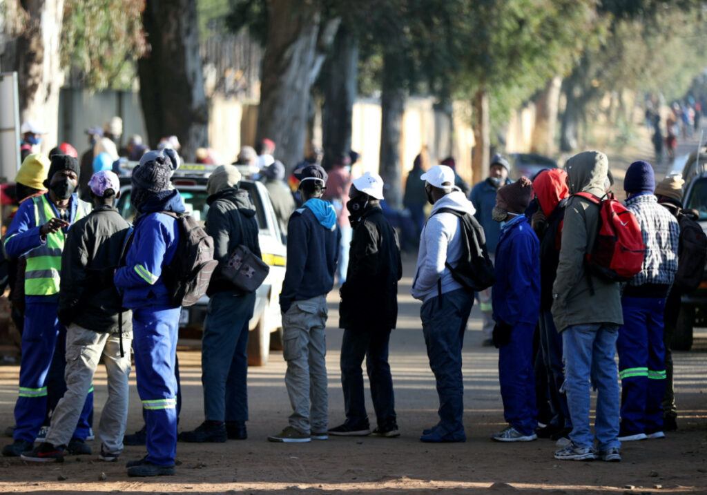 Job seekers stand outside a construction site ahead of the release of the unemployement numbers by Statistics South Africa, in Eikenhof, south of Johannesburg, South Africa, on 23rd June, 2020.
