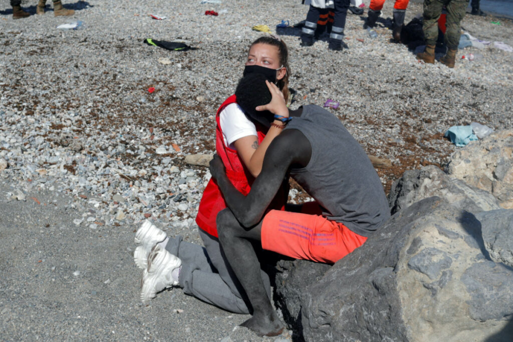Luna Reyes, 20, a member of Spanish Red Cross, embraces and comforts a migrant Sub-Saharian as he refuses to be deported to Morocco after he crossed the border swimming from Morocco to Spain, at El Tarajal beach, after thousands of migrants swam across this border during last days, in Ceuta, Spain, on 18th May, 2021