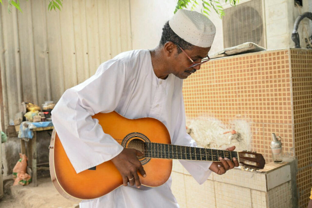 El Safi Mahdi, Sudanese music professor plays guitar as he waits to travel to his Sudanese musician wife Sohair Saddig Ali, who fled the fighting following the crisis, at the theatre of Novelists and Artists Union in the city of Port Sudan, Sudan, June 16, 2023. REUTERS/Ibrahim Mohammed Ishak