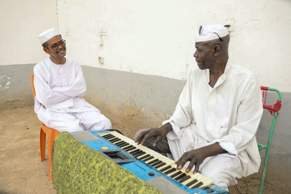 El Safi Mahdi, Sudanese music professor sits next to his friend playing keyboard, as he waits to travel to his Sudanese musician wife Sohair Saddig Ali, who fled the fighting following the crisis, at the theatre of Novelists and Artists Union in the city of Port Sudan, Sudan, on 16th June, 2023