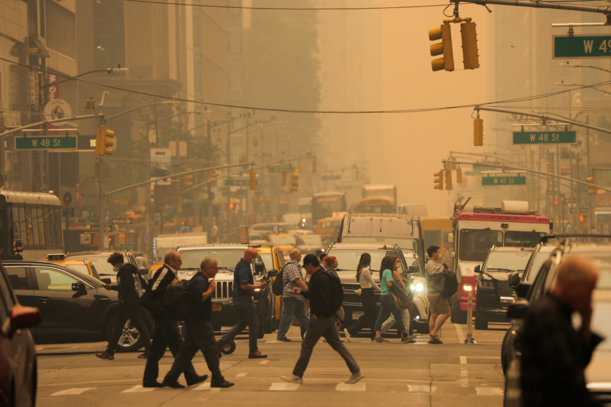 People walk at 6th Avenue as haze and smoke caused by wildfires in Canada blanket New York City, on 7th June, 2023
