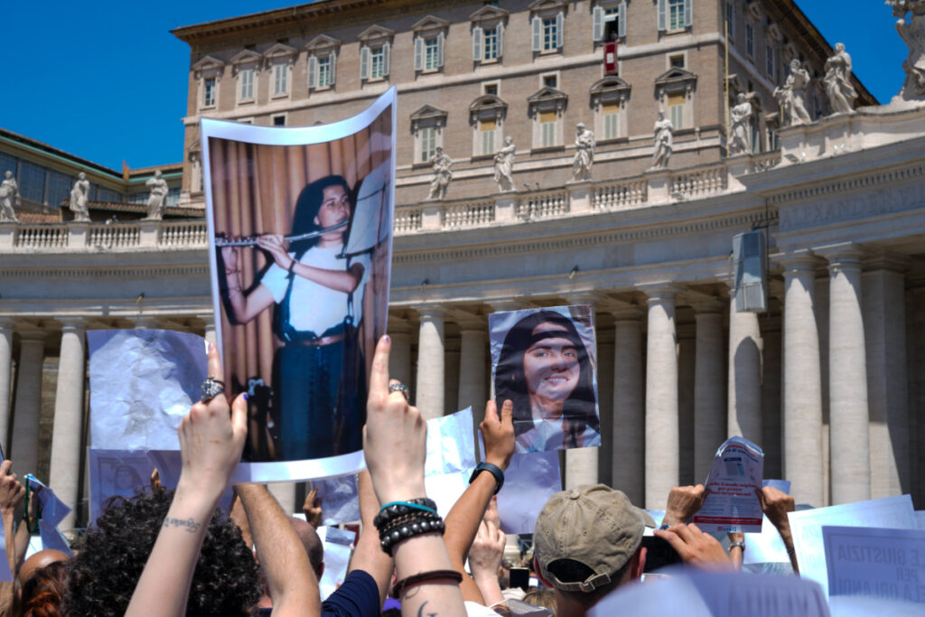 People hold pictures of missing girl Emanuela Orlandi during a sit-in in St Peter's Square as Pope Francis, at the window of his studio in background, recites the Angelus noon prayer, at the Vatican, on Sunday, 25th June, 2023.