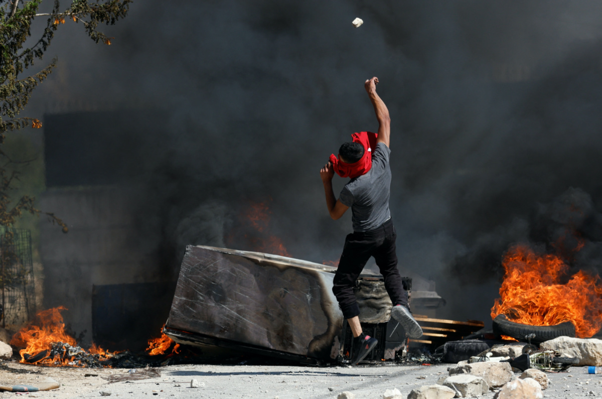 A Palestinian throws a stone during clashes with Israeli troops after Israeli settlers attack Umm Safa village near Ramallah, in the Israeli-occupied West Bank, on 24th June, 2023. 