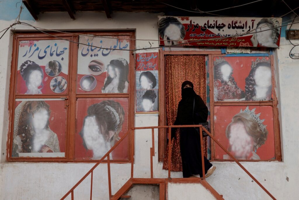 A woman wearing a niqab enters a beauty salon where the ads of women have been defaced by a shopkeeper in Kabul, Afghanistan, on 6th October, 2021.