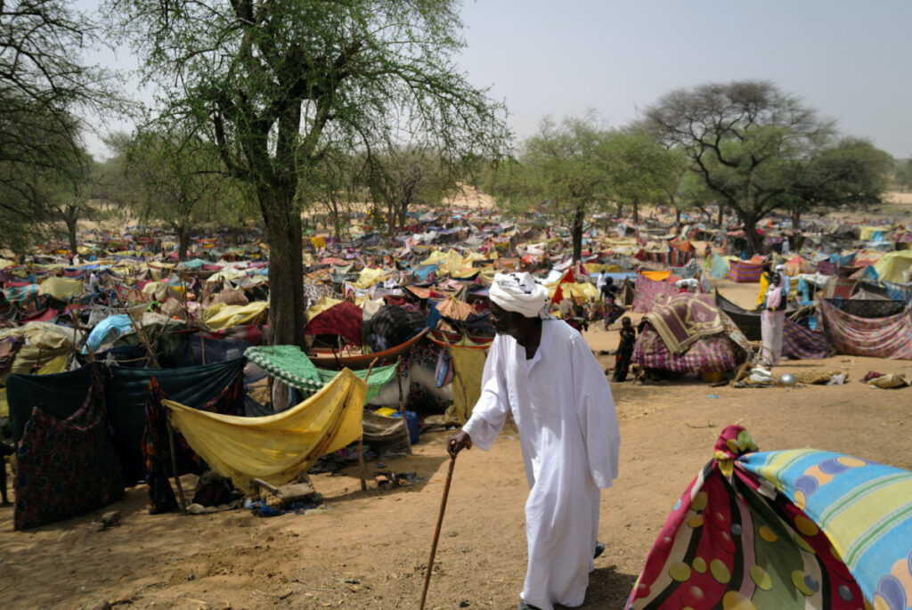 A Sudanese men who fled the conflict in Sudan's Darfur region, and was previously internally displaced in Sudan, walks past makeshift shelters near the border between Sudan and Chad, while taking refuge in Borota, Chad, on 13th May, 2023.