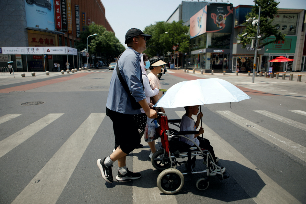Pedestrians cross a road on a hot day amid an orange alert for heatwave, in Beijing, China, on 16th June, 2023. 