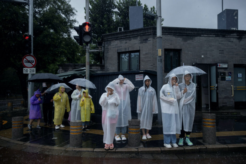 People wear raincoats in a tourist area during heavy rain in Beijing, China, on 30th July, 2023.