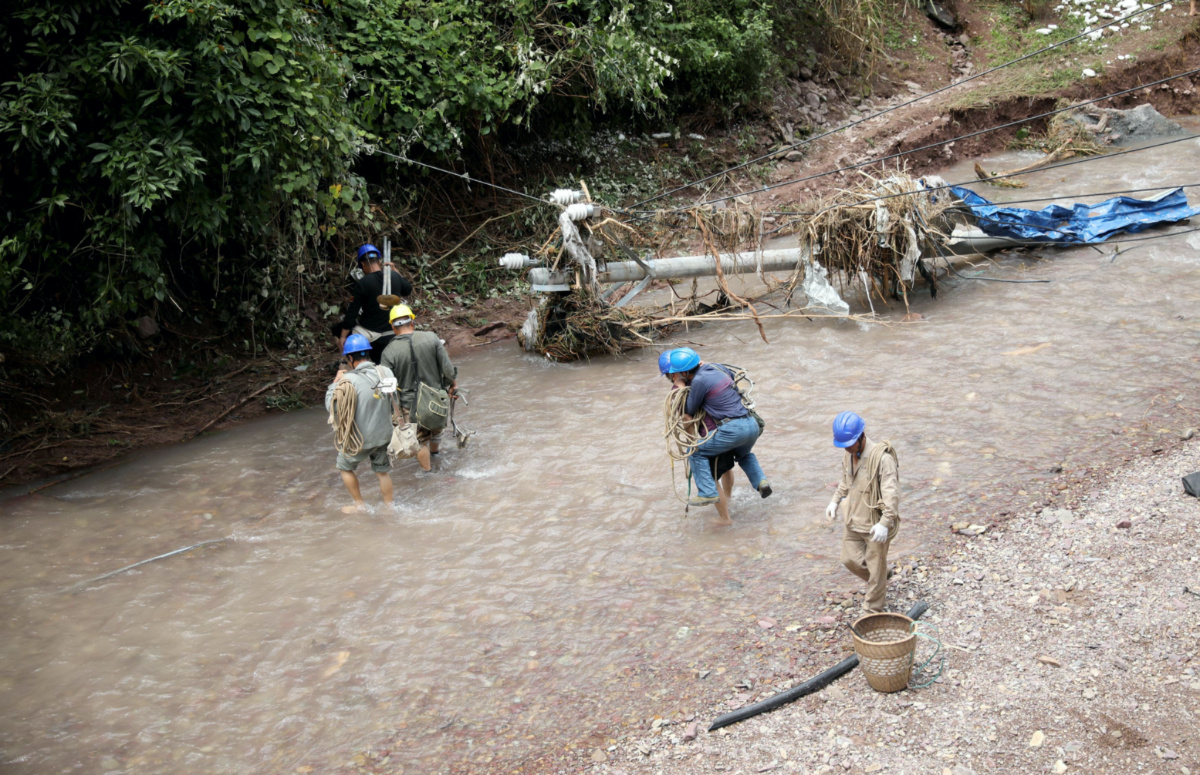 Electrical workers wade through waters next to a damaged power pole in Haogenping village, after heavy rainfall lashed Guzhang county in Xiangxi Tujia and Miao autonomous prefecture, Hunan province, China, on 2nd July, 2023. 