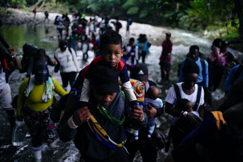 A Venezuelan migrant carries her son while crossing the Rio Muerto river in the Darien Gap, as they continue their journey to the US border, in Acandi, Colombia, on 9th July, 2023.