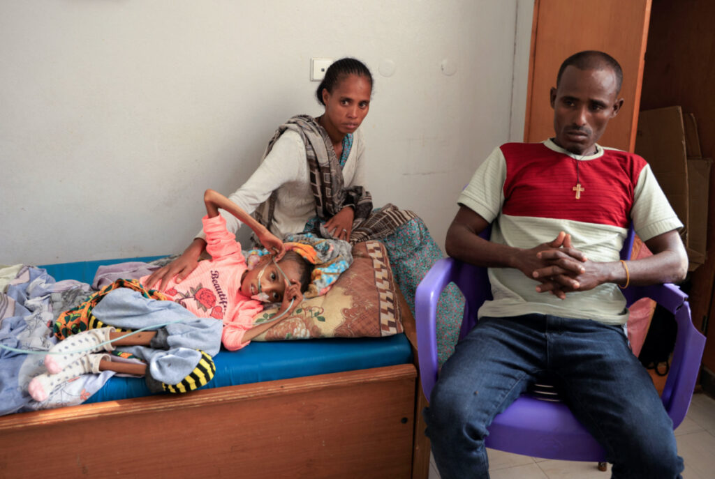 Tsige Shishay, 10, a severely malnourished girl weighing 10 kg due to food aid suspension from the United Nations World Food Program and the US Agency for International Development, lies on her bed next to her mother Abrehet Hadegay, 28, and her father Shishay Asmelash, 40, at the Ayder Referral Hospital in Mekele, Tigray Region, Ethiopia, on 22nd June, 2023.