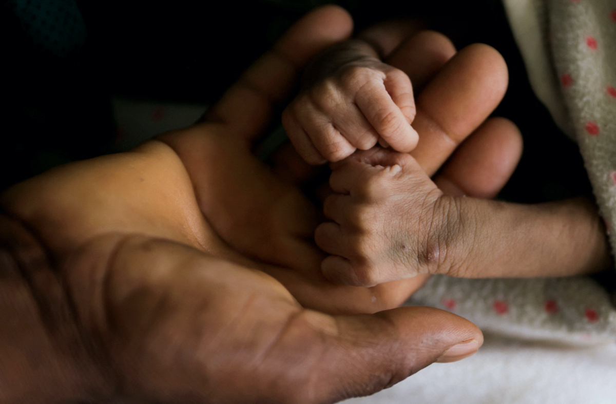 Woldegebrial Abadi, 36, holds the hands of his severely malnourished newborn son Berhanu Woldegebrial at the Samre Hospital, in Samre, Tigray Region, Ethiopia, on 23rd June, 2023.