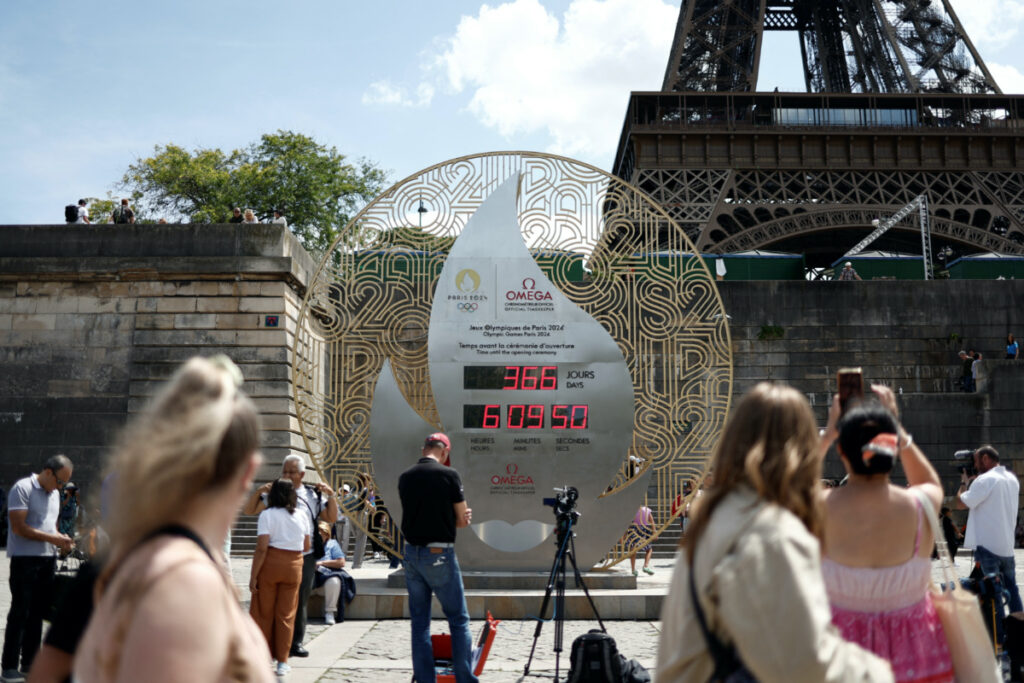 People walk past the countdown clock showing 366 days, one year to go until the Paris 2024 Olympic Games opening ceremony, near the Eiffel Tower in Paris, France, on 26th July, 2023.