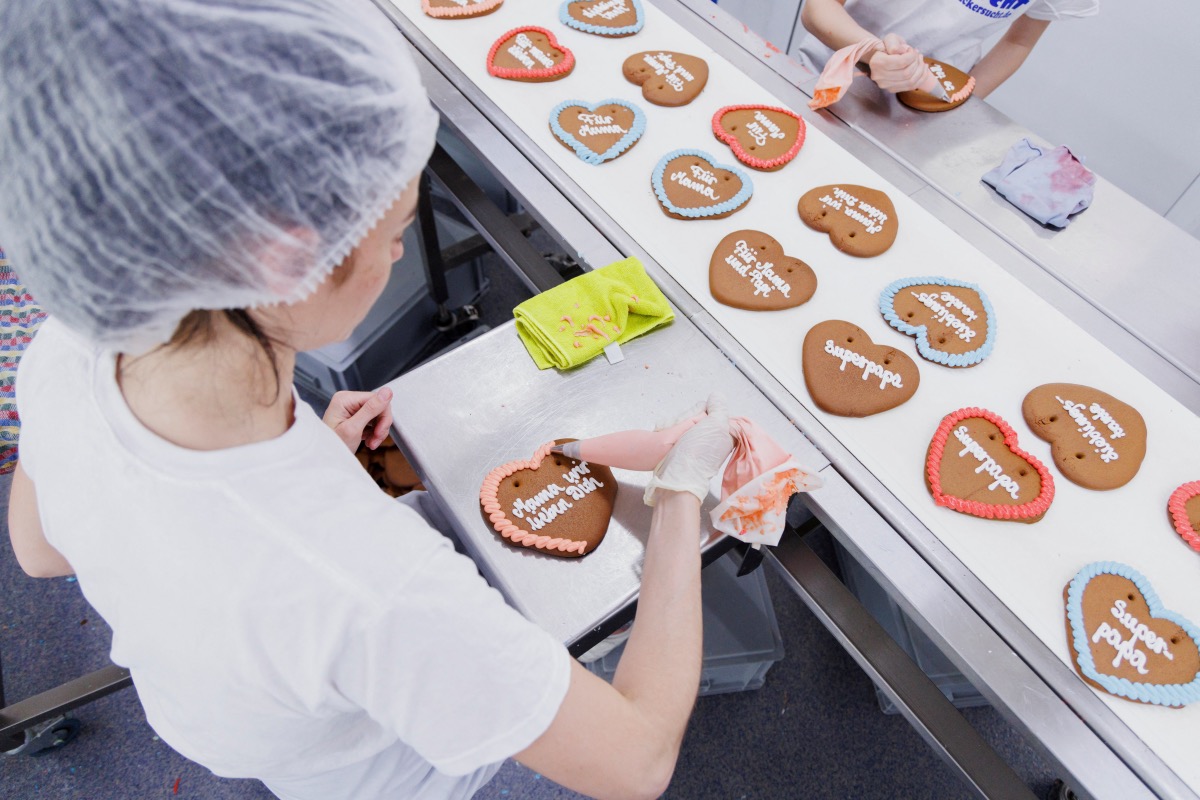 Maria, a refugee from Mykolaiv in Ukraine, decorates gingerbread Oktoberfest hearts at the 'Zuckersucht' bakery in Aschheim near Munich, Germany, 18th May, 2022. 
