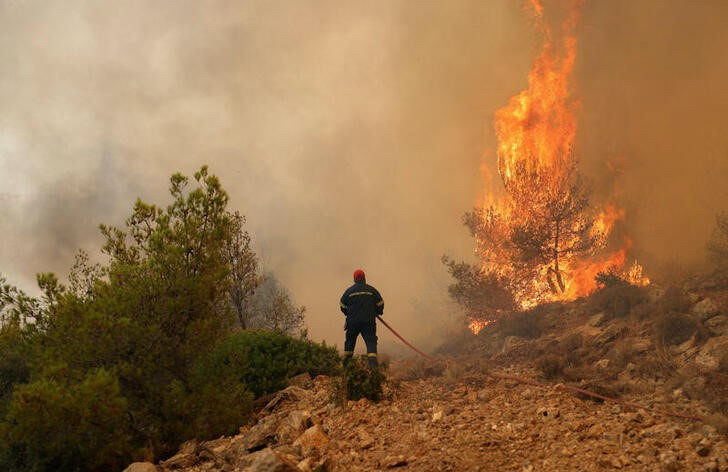 A firefighter tries to extinguish a wildfire burning near the village of Kandyli, near Athens, Greece, on 19th July, 2023.