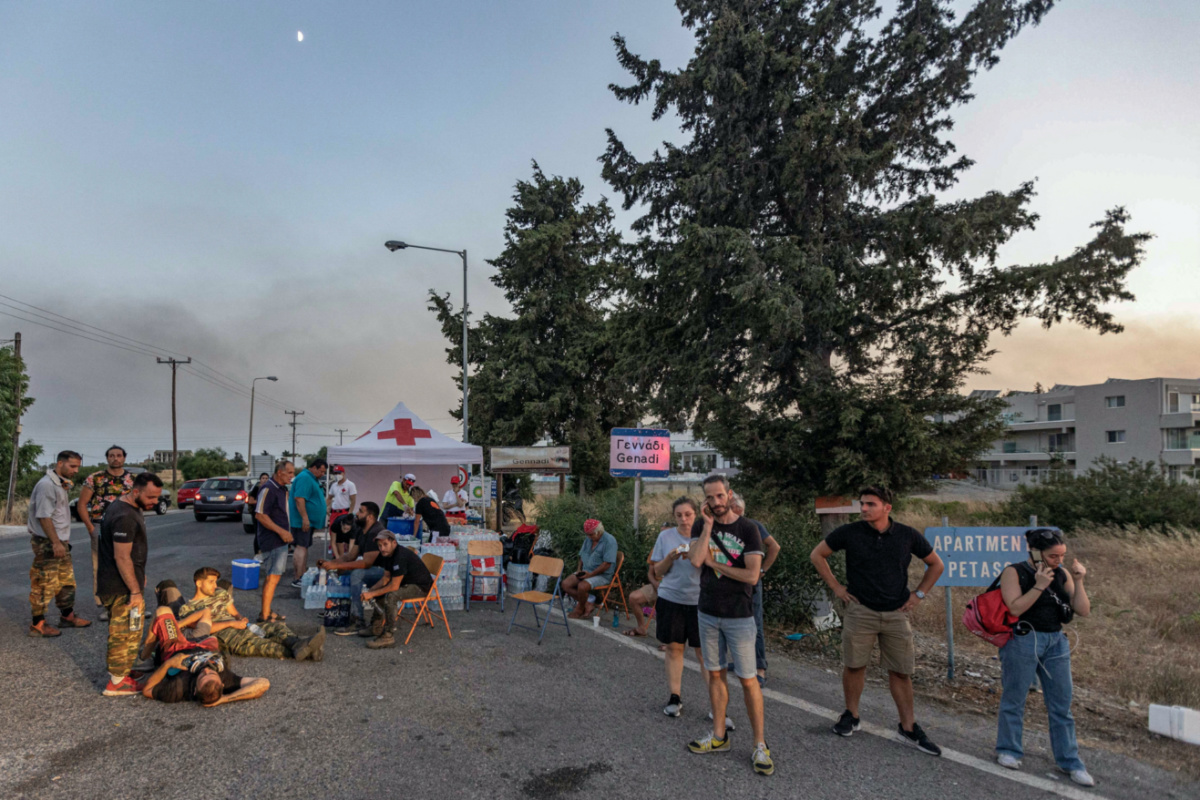 Volunteers rest at a gathering point as a wildfire burns in the village of Gennadi, on the island of Rhodes, Greece, on 26th July, 2023
