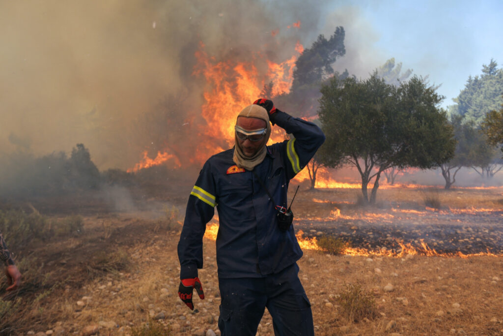 A firefighter walks next to rising flames as a wildfire burns near the village of Vati, on the island of Rhodes, Greece, on 25th July, 2023.