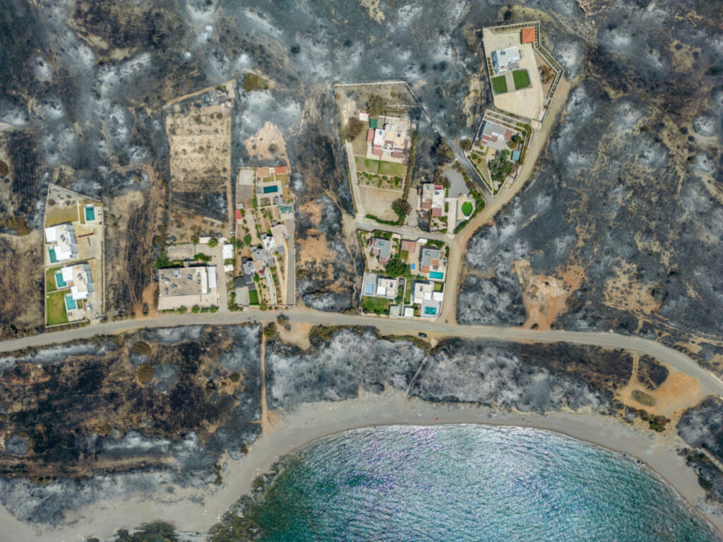 An aerial view of houses among burned land, as a wildfire burns on the island of Rhodes, Greece, on 27th July, 2023.