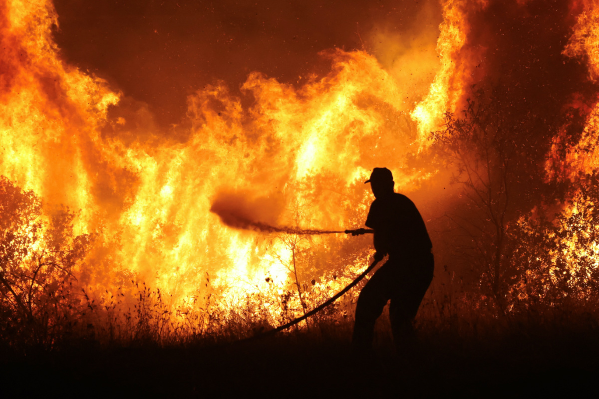 A firefighter tries to extinguish a wildfire burning at the industrial zone of the city of Volos, in central Greece, on 26th July, 2023. 