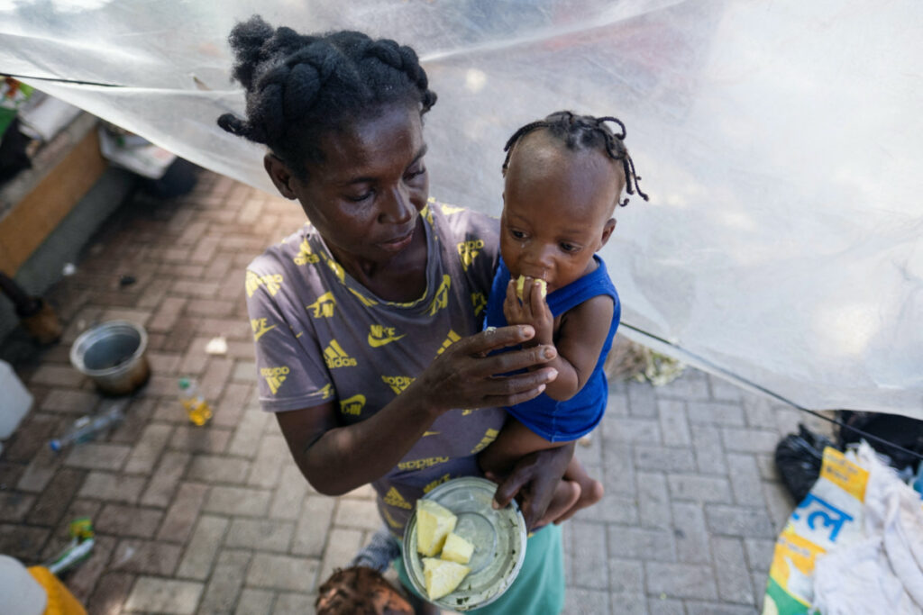 A woman feeds her baby at the Hugo Chavez Square where they shelter from gang war violence in Port-au-Prince, Haiti, on 16th October, 2022