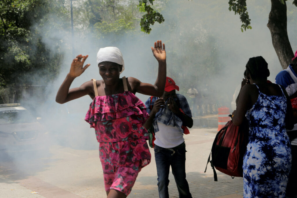 People move away from tear gas fired by officers of the Haitian National Police while clearing a camp of people escaping the threat of armed gangs, in front of the US Embassy, in Port-au-Prince, Haiti on 25th July, 2023.