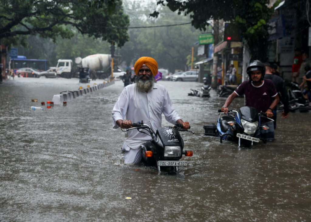 A man on his motorbike wades through a flooded street after heavy rains in New Delhi, India, on 8th July, 2023.