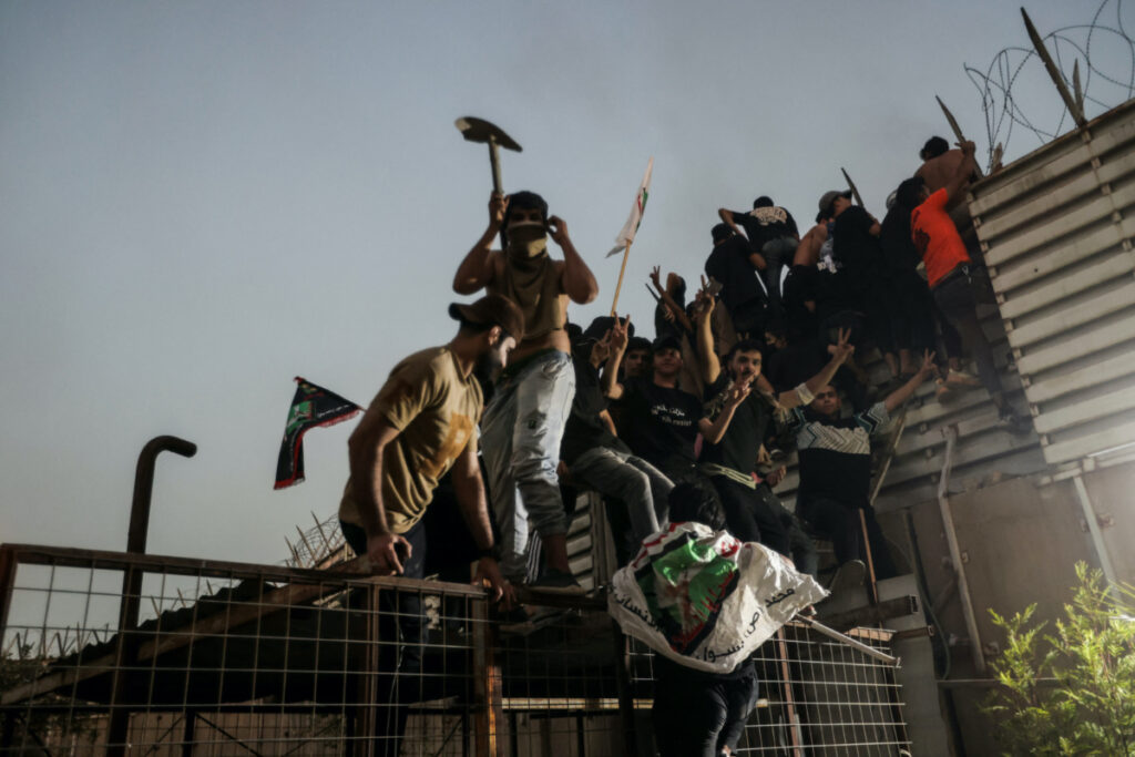 Protesters climb a fence as they gather near the Swedish embassy in Baghdad hours after the embassy was stormed and set on fire ahead of an expected Quran burning in Stockholm, in Baghdad, Iraq, on 20th July, 2023