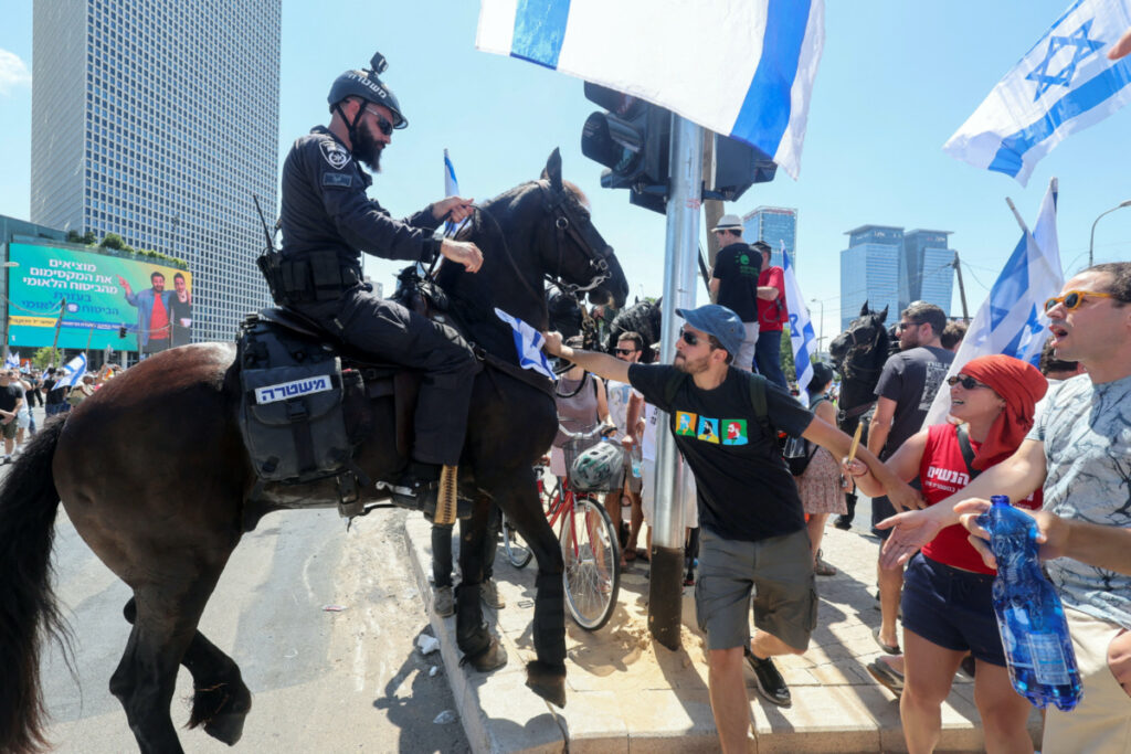 People confront with an Israeli police officer as they demonstrate on 'Day of Disruption' in protest against Israeli Prime Minister Benjamin Netanyahu and his nationalist coalition government's judicial overhaul, in Tel Aviv, Israel, on 11th July, 2023