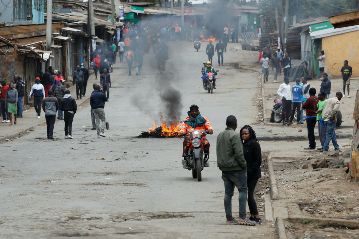 A person rides a bike past tyres set on fire by protestors in Kibera slum during an anti-government protest against the imposition of tax hikes by the government in Nairobi, Kenya, on 19th July, 2023. 
