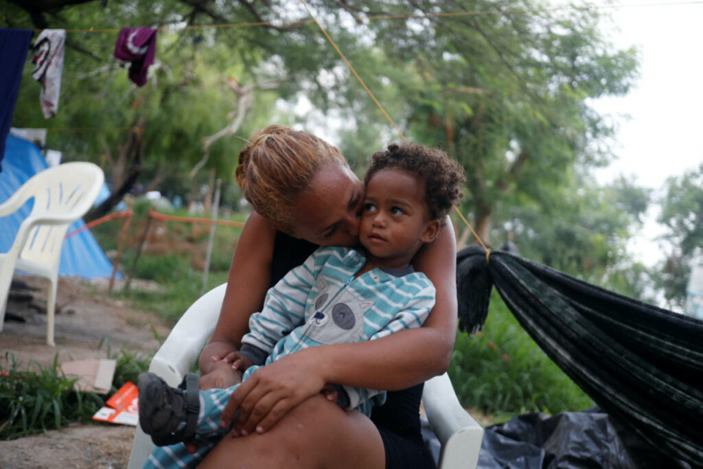 Venezuelan asylum seeker Alejandra Pena, 34, kisses her son Natanael, one, next to their tent, while they wait to attempt to cross into the US by an appointment through the Customs and Border Protection app, called CBP One, at a makeshift camp, in Matamoros, Mexico, on 20th June, 2023.