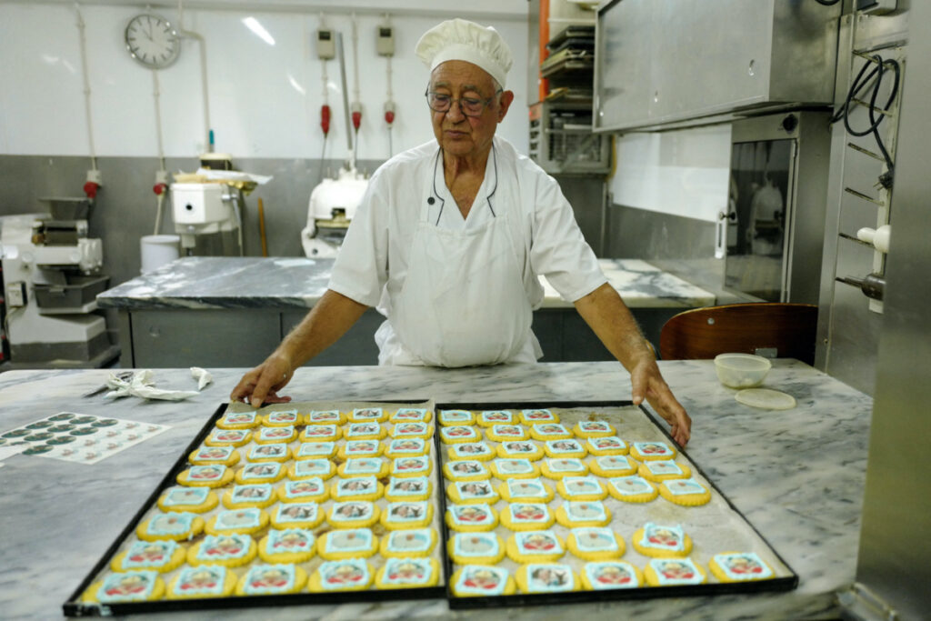 A pastry chef stands beside cookies with Pope Francis images ahead of his apostolic journey to Portugal on the occasion of the XXXVII World Youth Day, in Lisbon, Portugal, on 26th July, 2023.