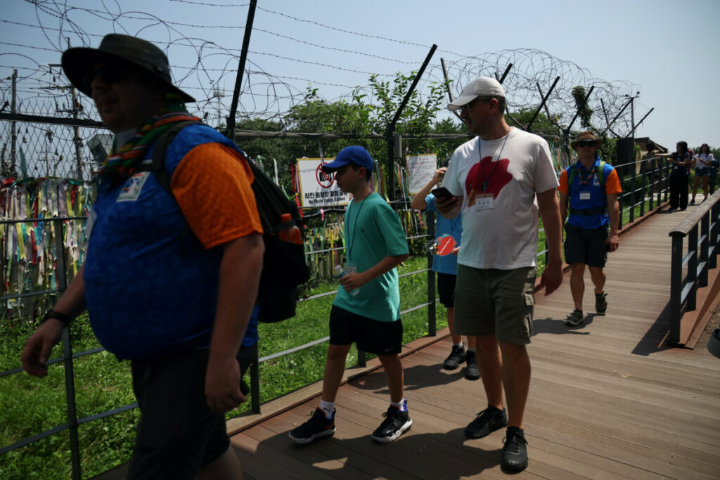 Foreign tourists participating in DMZ tour walk past a military fence near the demilitarized zone separating the two Koreas, in Paju, South Korea, on 19th July, 2023.