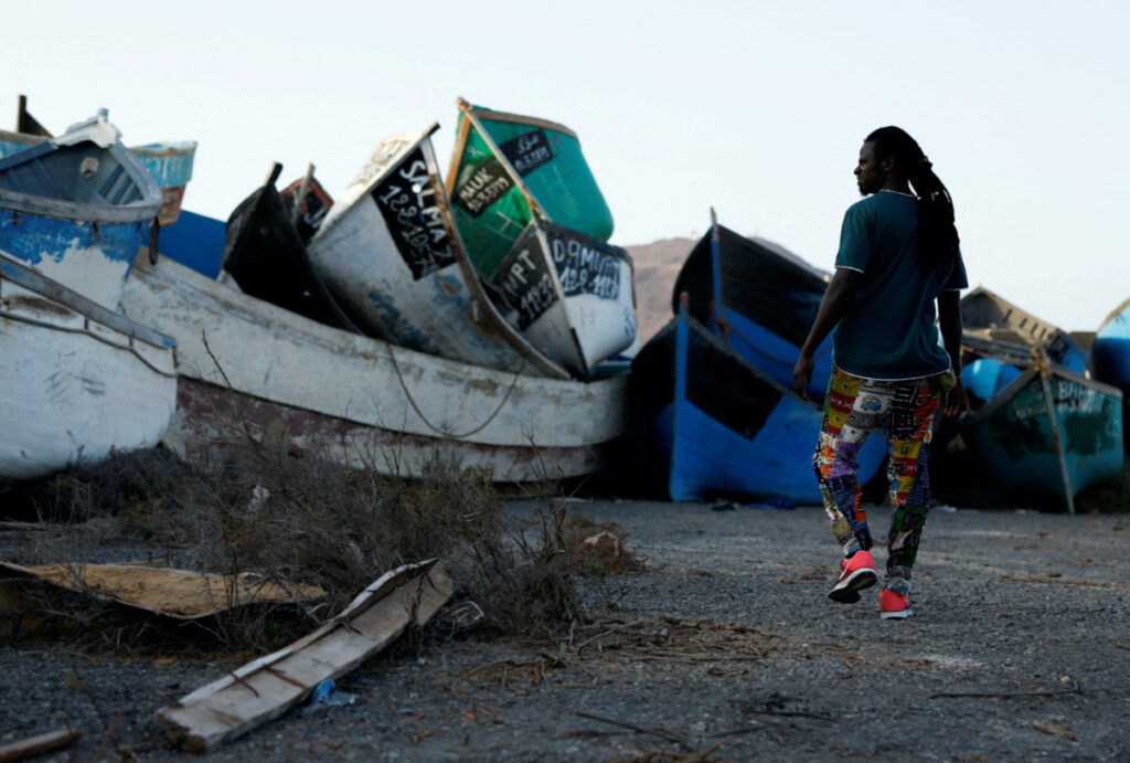 A migrant from Senegal, Mohamed Fane, who arrived in wooden boat to the Spanish island of Gran Canaria walks in a cemetery of abandoned wooden boats in Arinaga. Spain, on 4th August, 2022.