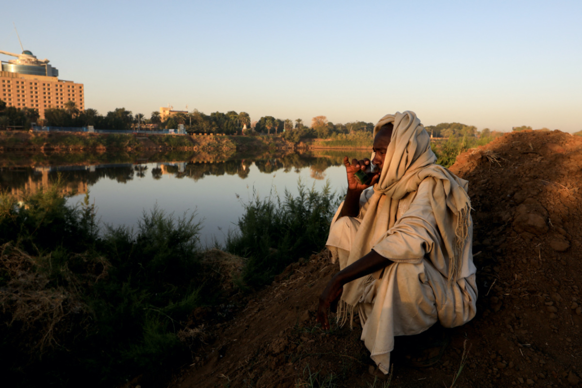 Mohamed Ahmed al Ameen, 55, a brick maker, drinks a cup of tea as he sits on the edge of the Blue Nile near an open-air factory on Tuti Island, Khartoum, Sudan, on 14th February, 2020. 