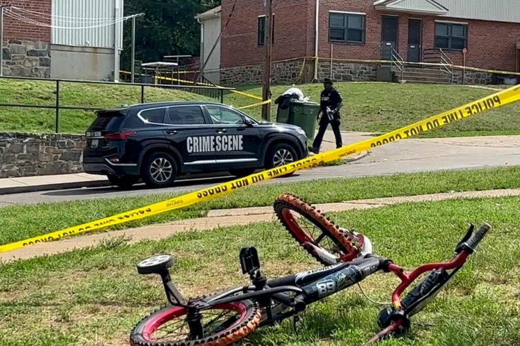 A police officer passes a child's bicycle after a mass shooting at the scene of a Fourth of July holiday weekend block party in Baltimore, Maryland, US, on 2nd July, 2023 in a still image from video