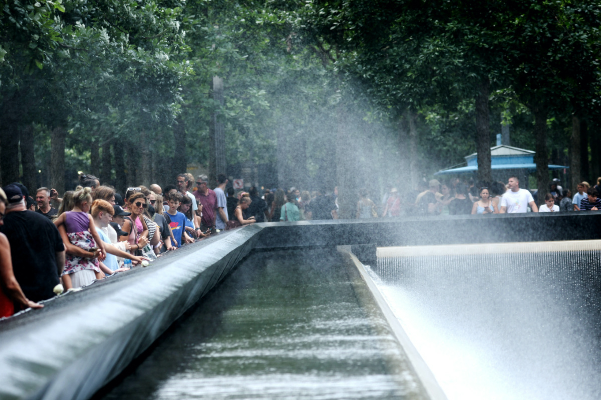 People cool off with a spray from the north reflecting pool, at the 911 Memorial and Museum, during hot windy weather in lower Manhattan in New York City, New York, US, on 27th July 2023.