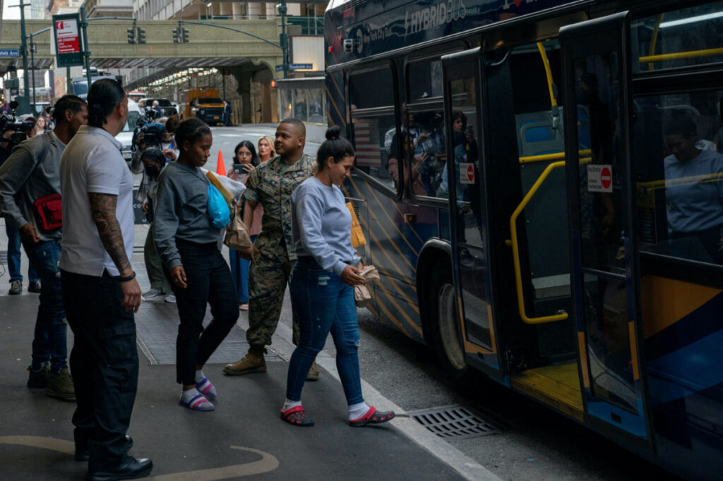 People exit the Roosevelt Hotel where asylum-seeker are currently being housed onto an MTA. bus in New York City, US, on 19th May, 2023.