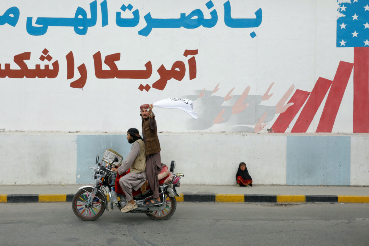 A Taliban supporter holds an Islamic Emirate of Afghanistan flag on the first anniversary of the fall of Kabul on a street in Kabul, Afghanistan, on 15th August, 2022